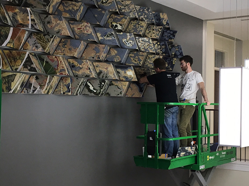 Workers install the new artwork in Shideler Hall, which was recently renovated.